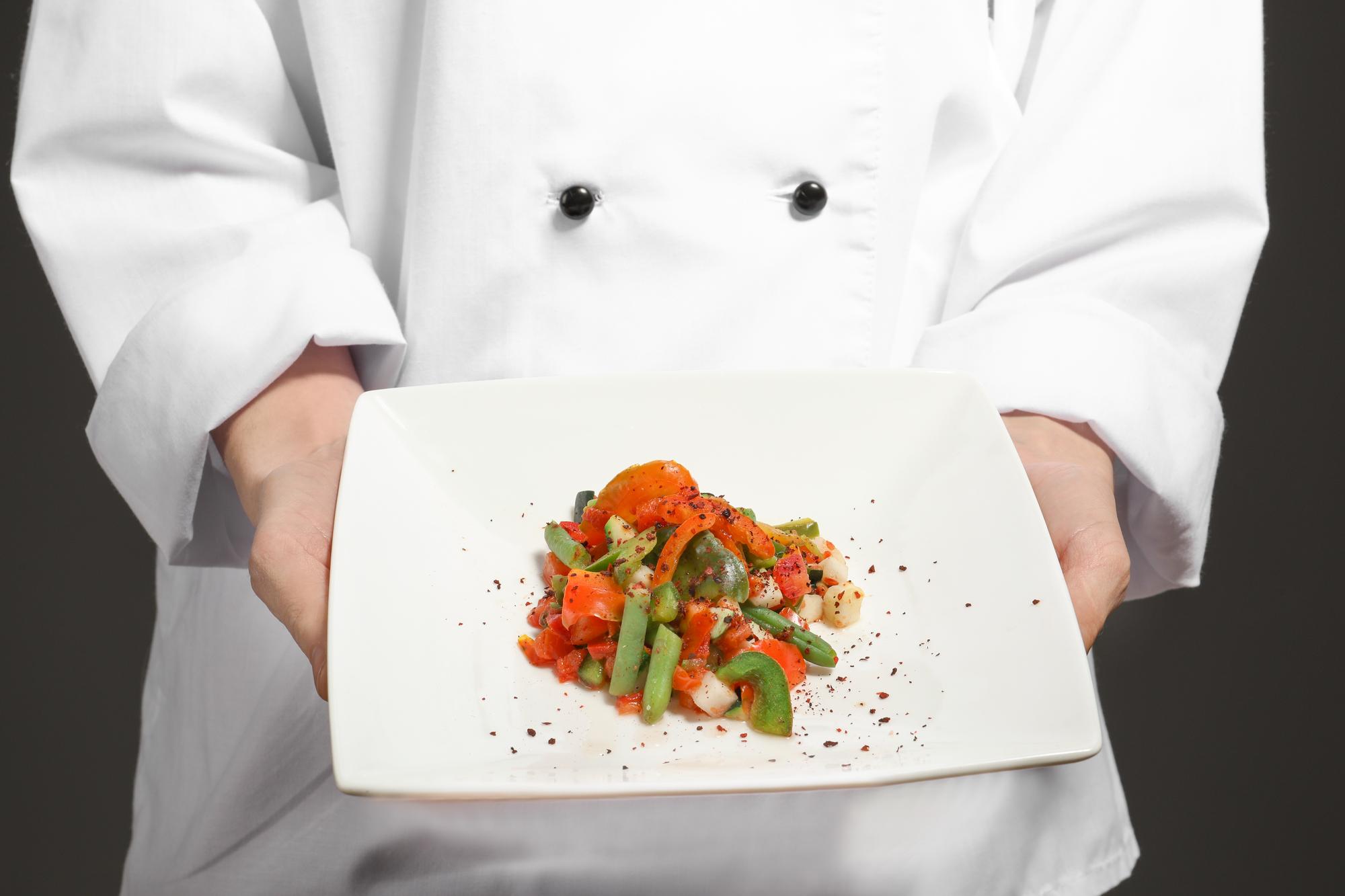 Chef che mostra una preparazione su un tavolo moderno